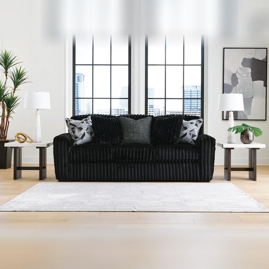 Midnight Madness Onyx jumbo corduroy sofa with accent pillows, styled in a loft living room with tall black-framed windows