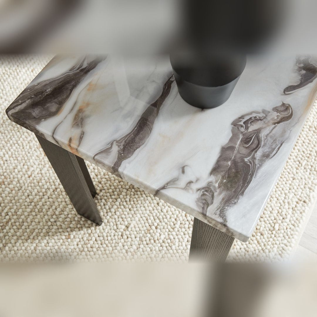 Close-up of a Jazmore end table leg meeting the faux marble top, on a woven rug