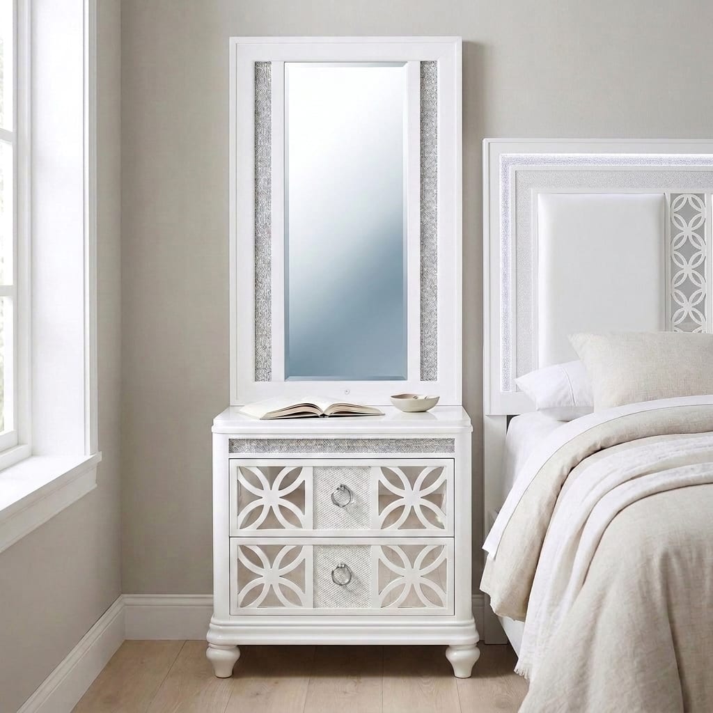 Abigale white mirror-top nightstand in daylight beside the matching Abigale panel bed, its tall framed mirror centered on the top surface, circular-lattice drawer fronts and chrome ring pulls